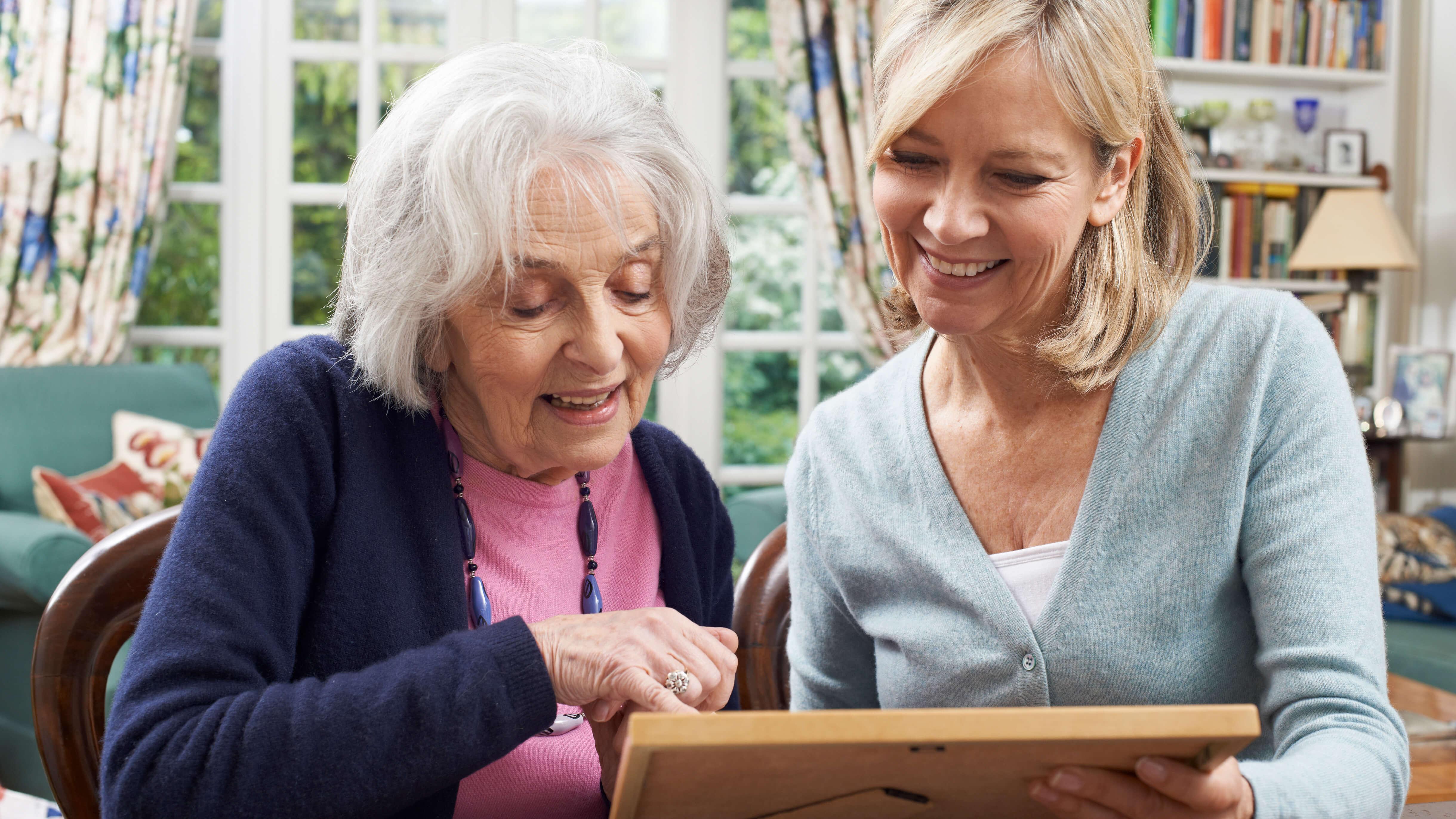 two women sitting at a table looking at a picture