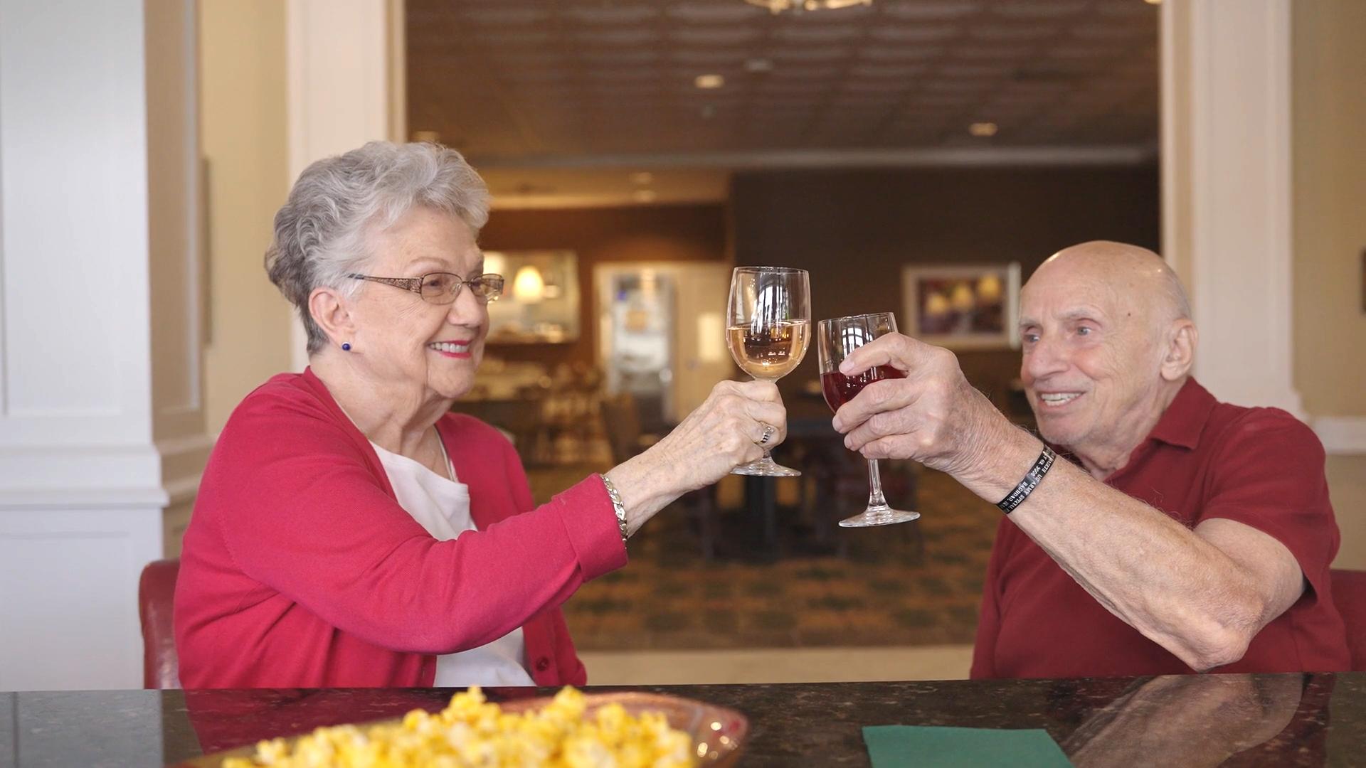 a senior couple toasting to each other at a table
