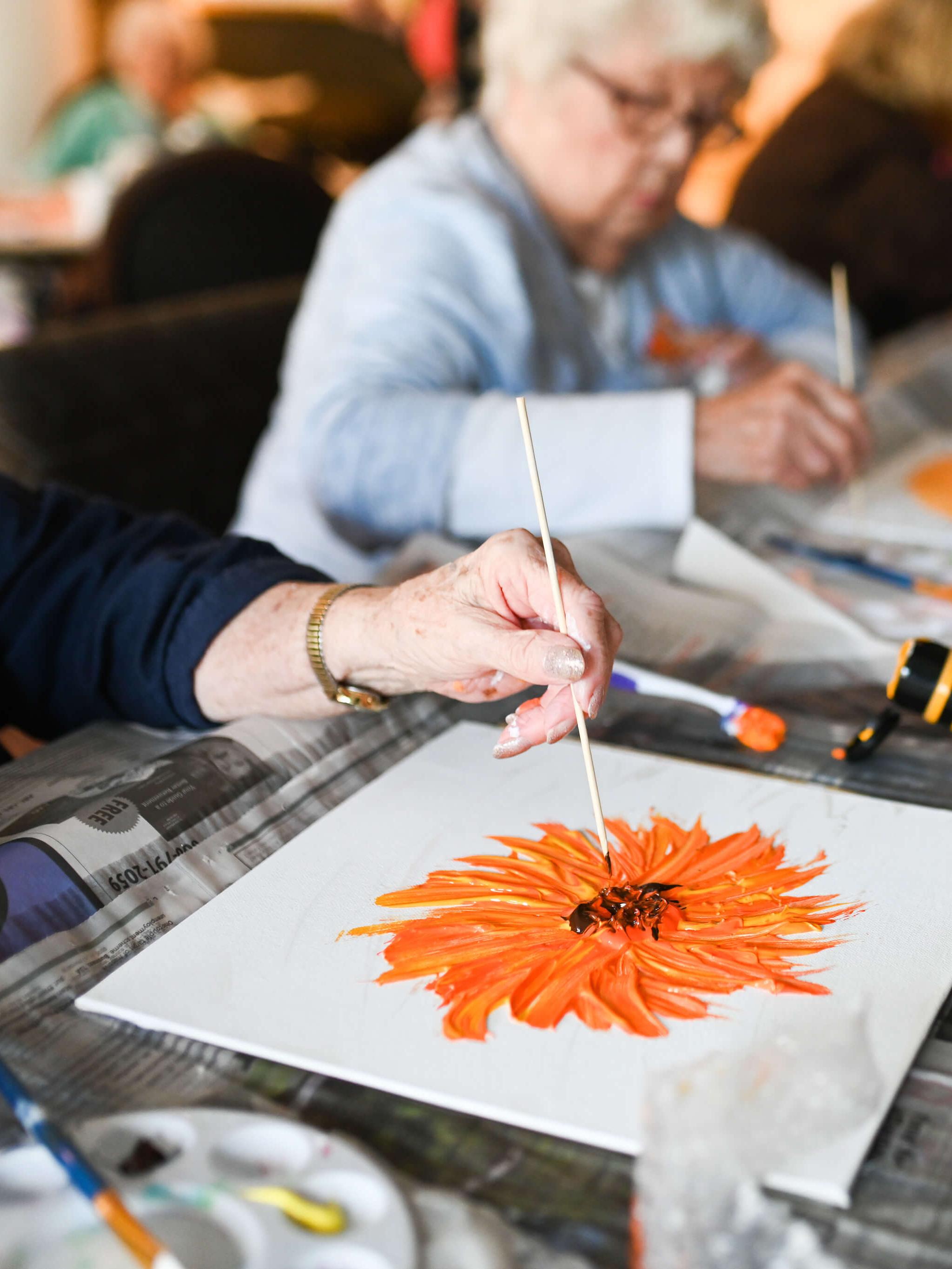 Woman painting an orange flower on canvas