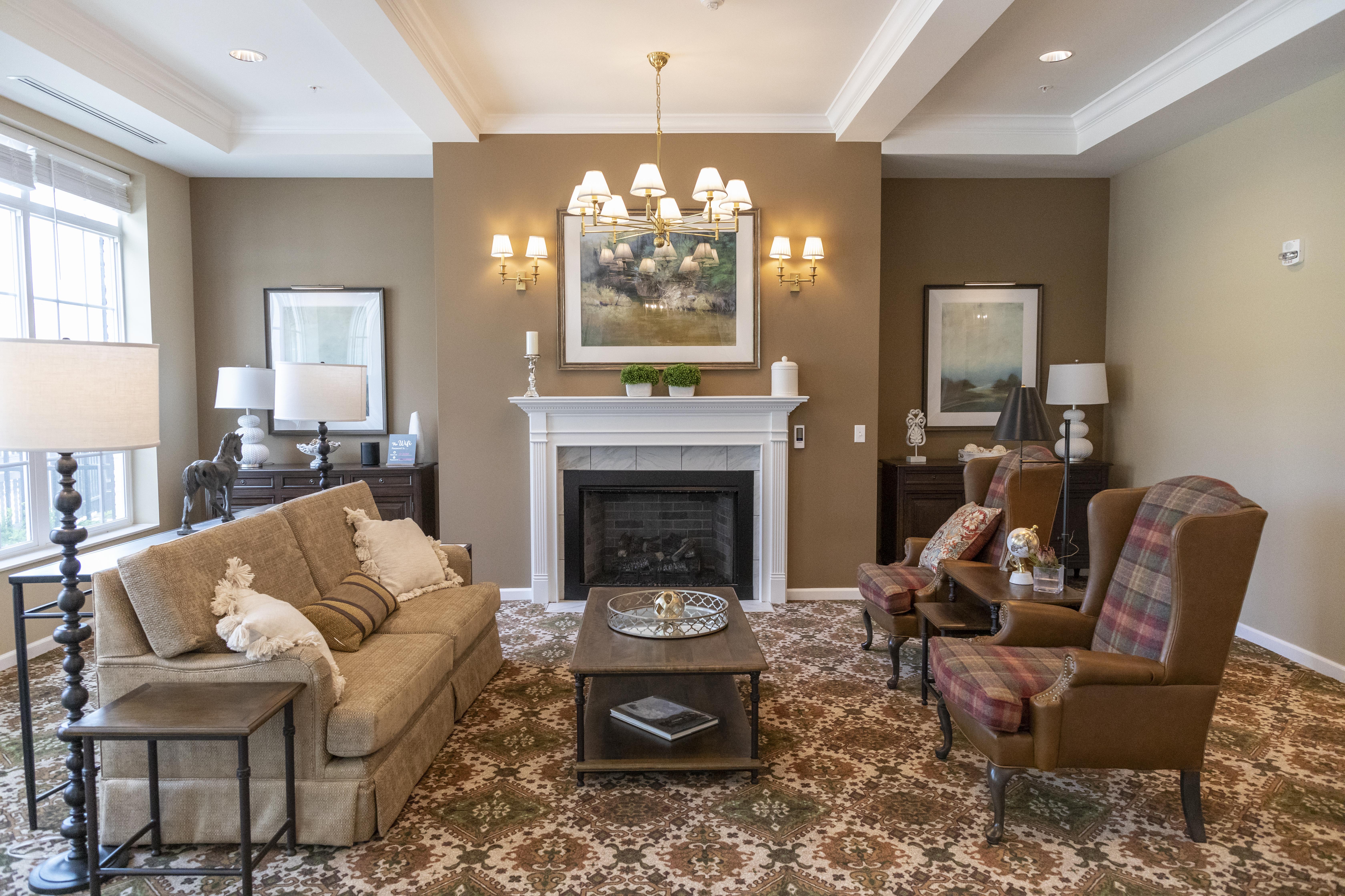 Cozy living room setup with a beige sofa, wingback chairs, fireplace, and elegant lighting