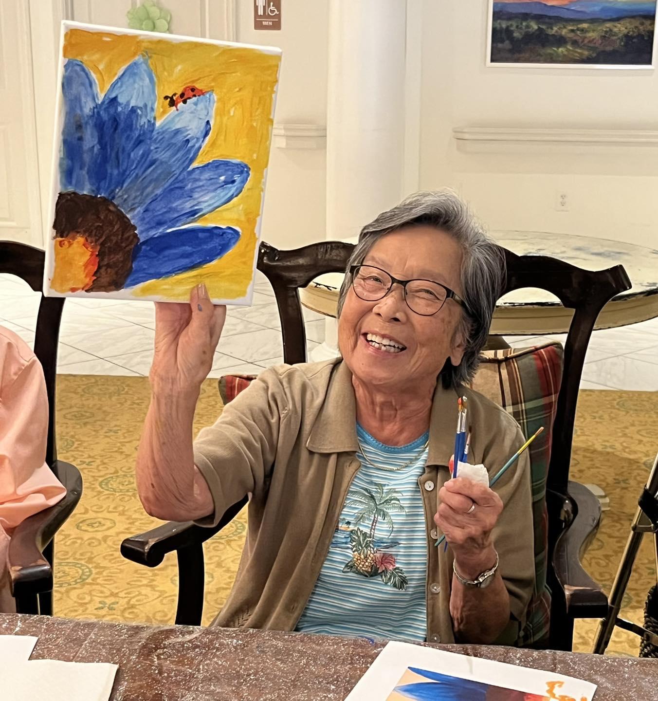 Older woman holding up a painting she made